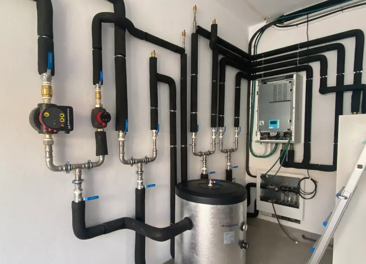 Instalación de aerotermia en Madrid: circuito hidráulico con bombas, válvulas y acumulador de agua caliente montado en sala técnica