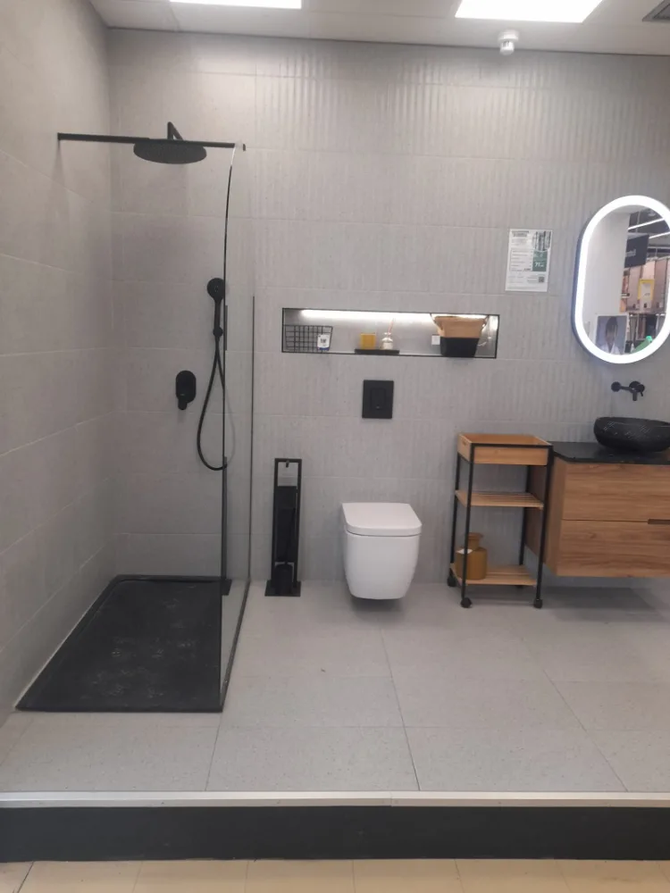 Baño terminado en una reforma de JM Reformas Élite: ducha de obra con grifería negra, mueble suspendido de madera e inodoro suspendido